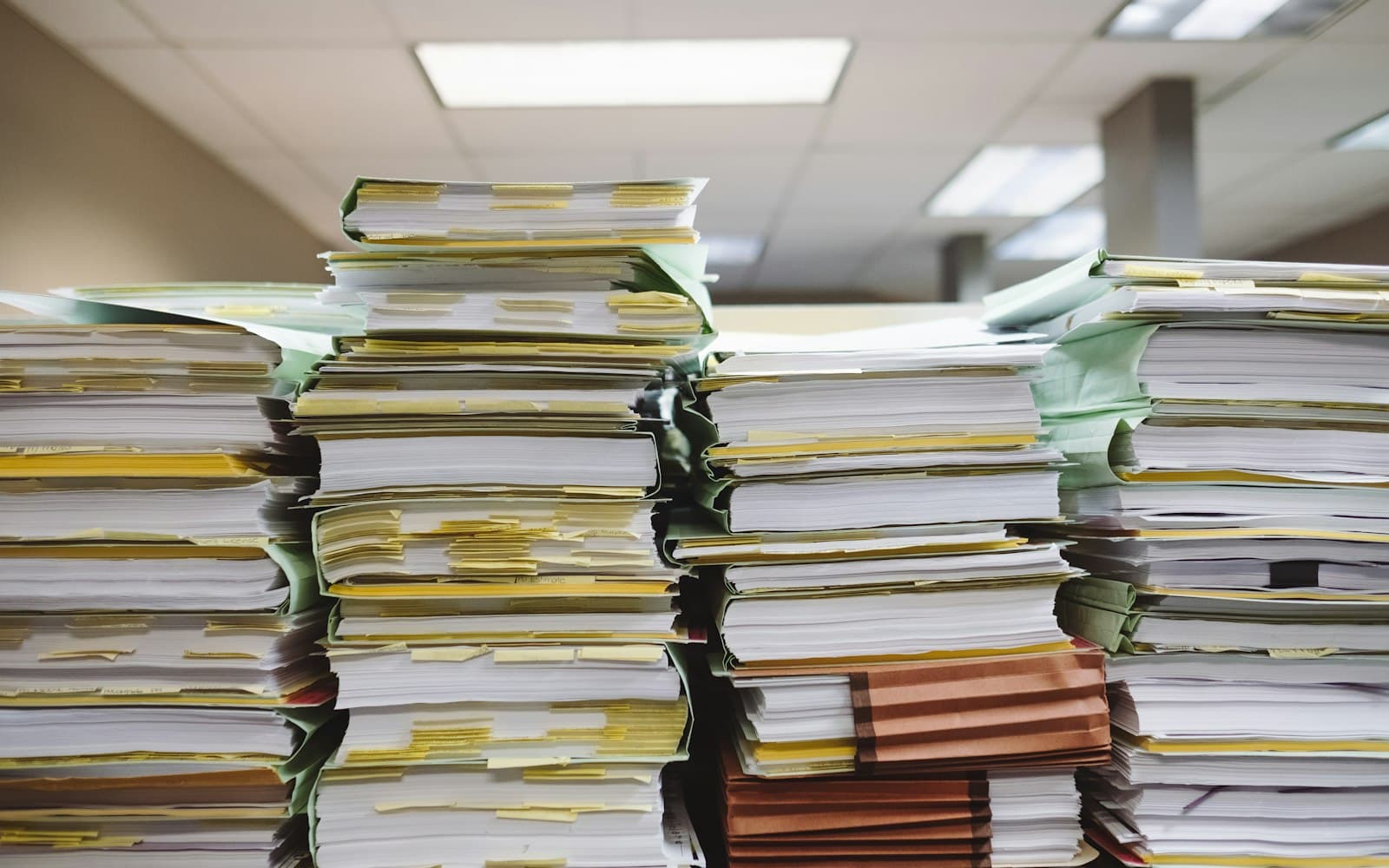 Stacks of paper files piled on an office desk