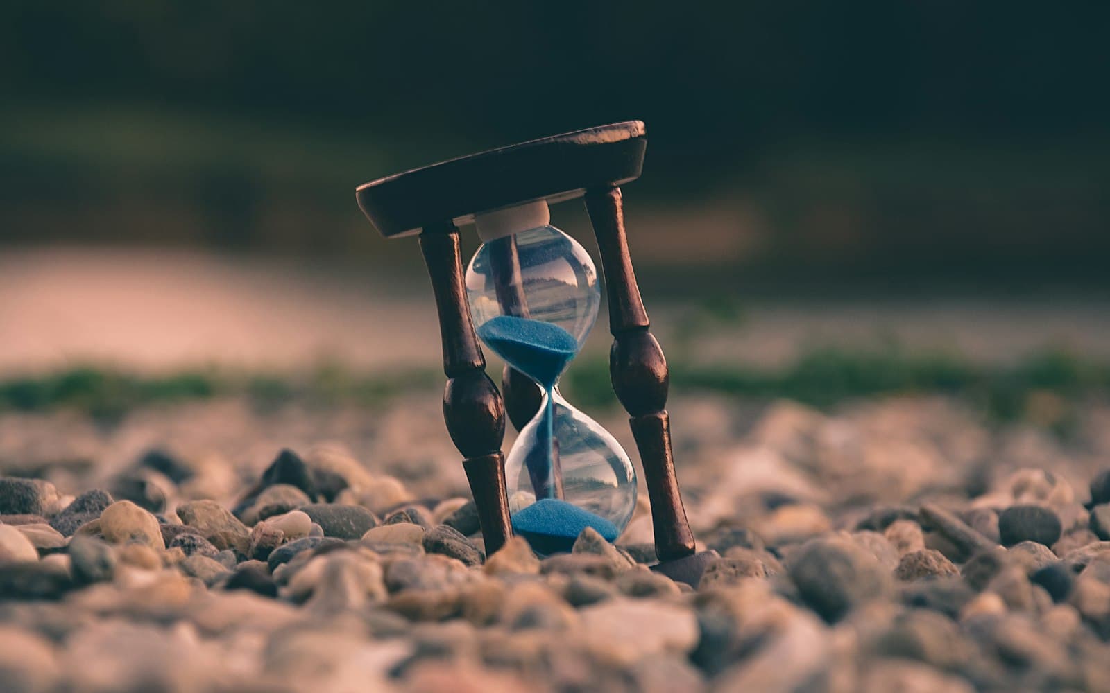 An hourglass standing on a bed of pebbles