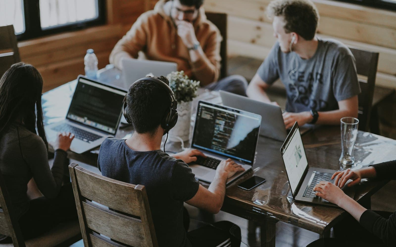 A team working together on laptops around a wooden table