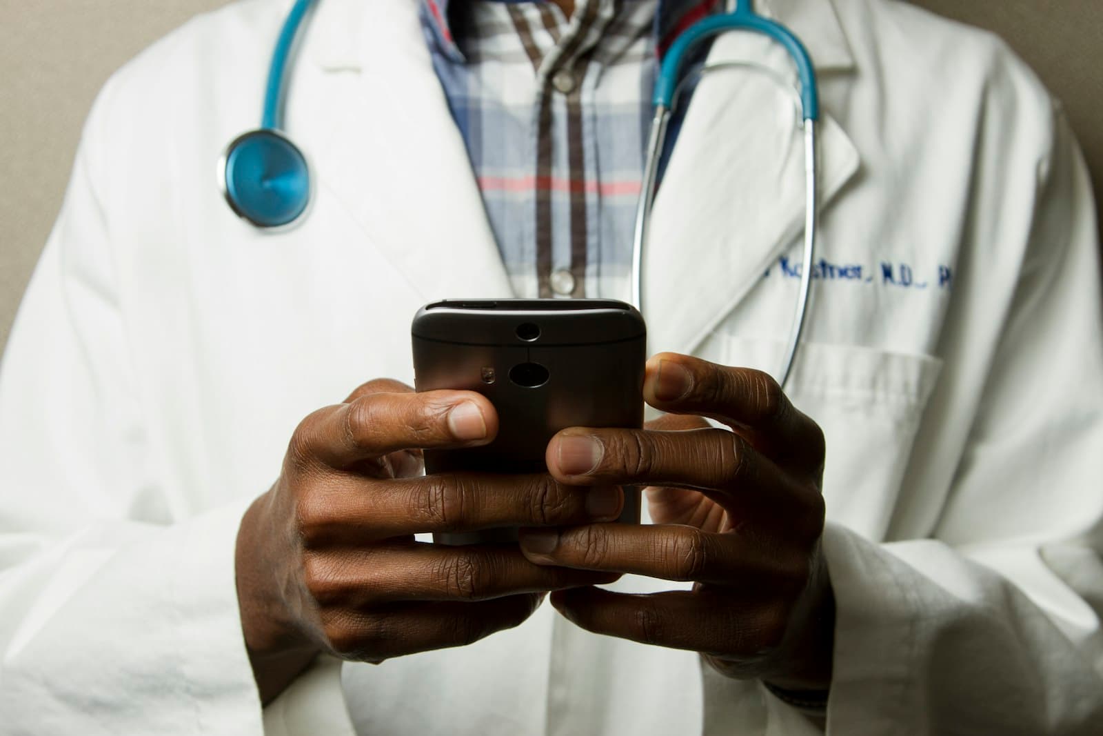 A clinician in a white coat using a phone