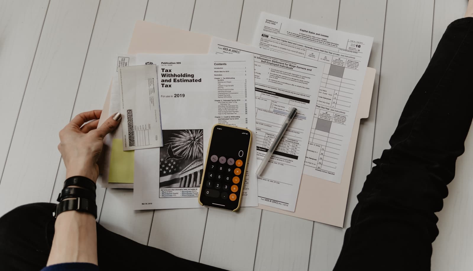 Financial paperwork, a calculator and a pen spread across a desk